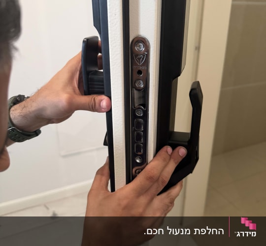 אדם מתקין מנעול על דלת לבנה